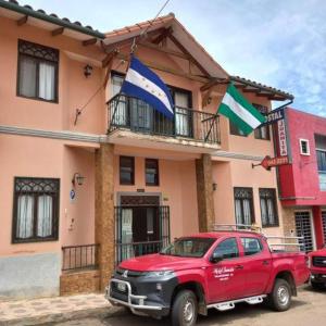 Vallegrande的住宿－Hostal Juanita，停在有旗帜的建筑前的一辆红色卡车