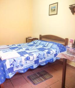 a bedroom with a bed with a blue and white quilt at Hostal Juanita in Vallegrande