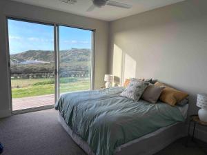 sypialnia z łóżkiem i dużym oknem w obiekcie Middle River Vista Beach House w mieście Stokes Bay