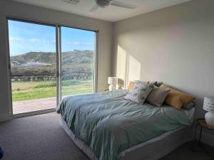 a bedroom with a bed and a large window at Middle River Vista Beach House in Stokes Bay