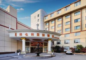 a hotel with a fountain in front of a building at Vienna International Hotel - Shanghai Jiaotong University Humin Road in Shanghai