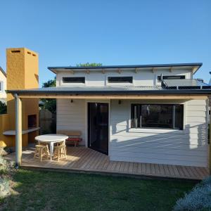 a house with a deck with a table on it at Brand new cottage, walk to beach - inverter, wi-fi, DSTV in Cape St Francis