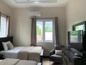 a bedroom with two beds and a tv and a chair at lovely gated 3 BEDROOM in Kingston