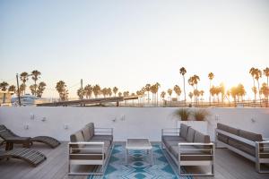 een patio met stoelen, een tafel en palmbomen bij The Redline Venice in Los Angeles