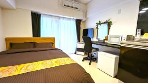 a bedroom with a bed and a desk and a microwave at KIYAZA Station Sapporo 2 in Sapporo