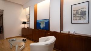 a living room with a white chair and a tv at Quiet City Center Apt on a Pedestrian Street in Athens +21 photos