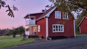 Casa roja con ventanas blancas y porche en Lantligt hus på Knohult, en Aneby