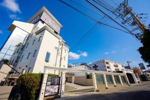 ein weißes Gebäude an der Straßenseite in der Unterkunft ホテル シードット 横浜 トレ in Yokohama