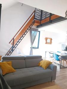 een woonkamer met een bank en een trap bij Appartement duplex dans une ancienne usine in Beaupréau