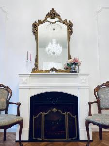 a fireplace with a mirror and two chairs at LittleParis in Cluj-Napoca