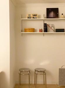 two stools sitting next to a wall with shelves at TAB Apartment in Busan