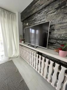 a living room with a large television on a stone wall at Apartament 2 camere Mogoșoaia in Mogoşoaia