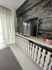 un soggiorno con grande TV su un muro di pietra di Apartament 2 camere Mogoșoaia a Mogoşoaia