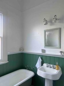 baño verde y blanco con bañera y lavamanos en Breen Green House en Quarry Hill