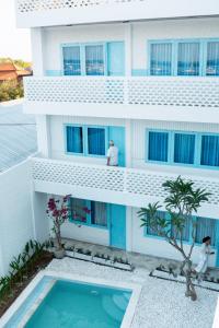 two people standing on the balcony of a building with a swimming pool at Paras Paros Marina Lodge in Sanur