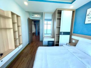 1 dormitorio con cama blanca y pared azul en Mường Thanh Luxury Viễn Triều Apartment en Nha Trang