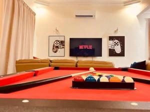 a living room with a red pool table with balls at Modern Family Retreat by STAYco - PS4, Mini-Pool, Pool table - just 5 mins to Beach ! in Ayer Itam