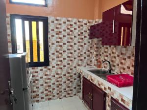 a kitchen with a sink and a tiled wall at Appartement Spacieux chez Keur Matou - F2 Dakar in Dakar +19 photos