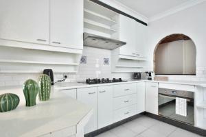 a white kitchen with white cabinets and a cactus at 3 Bedrooms - Darling Harbour - Darghan Street 2 E-Bikes Included in Sydney