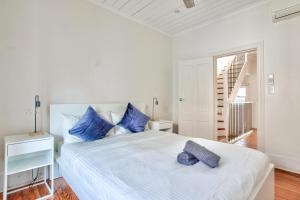 a white bedroom with a large white bed with blue pillows at 3 Bedrooms - Darling Harbour - Ada Place in Sydney