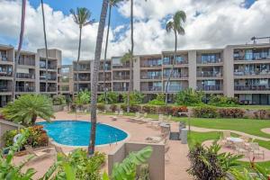 an apartment complex with a swimming pool and palm trees at Hale Ono Loa 403- Top floor, Ocean view, & complete modern remodel in Kahana
