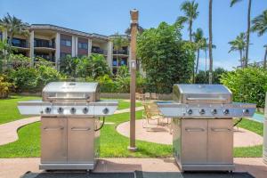 two bbqurgers on a patio in front of a building at Hale Ono Loa 403- Top floor, Ocean view, & complete modern remodel in Kahana