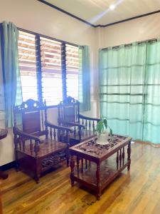 a living room with a table and chairs and windows at Maria Kulafu Kubo House Kinamaligan beside Eglin Gas Station 