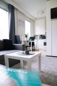 a living room with a white table and a kitchen at Railway&bus station studio in Oulu +6 photos