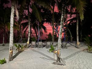 a beach with chairs and palm trees and a sunset at Cap Jean Marie Beach Villas in Anse Kerlan