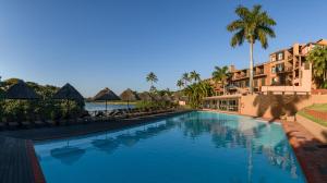 uma piscina num resort com palmeiras e edifícios em San Lameer Villa 2909 em Southbroom