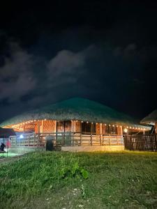 ein großes Gebäude mit Grasdach in der Nacht in der Unterkunft Maria Kulafu Kubo House Kinamaligan beside Eglin Gas Station 
