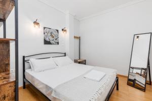 - une chambre blanche avec un lit et un miroir dans l'établissement Stavroula's House City Center, Penthouse, à Thessalonique