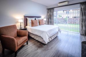 a bedroom with a bed and a chair and a window at Olden Rose Place in Lephalale