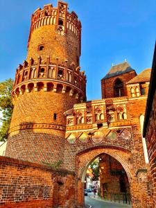 um grande edifício de tijolos com uma torre e um arco em Lehmhäuschen mit Sauna em Tangermünde