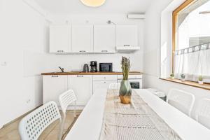 a white kitchen with a table and white chairs at Chic & Modern Apartment in Jüterbog