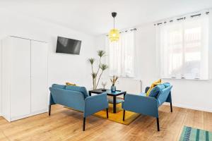 sala de estar con 2 sillas azules y mesa en Chic & Modern Apartment, en Jüterbog