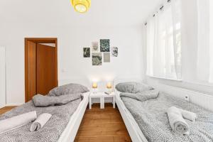 two beds in a white room with a table at Chic & Modern Apartment in Jüterbog