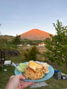 a person holding a plate of food with a plate of food at Bengker Bungalow in Sembalun Lawang