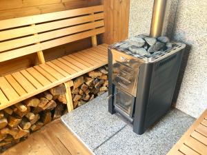 a stove sitting next to a bench next to a pile of logs at Lehmhäuschen mit Sauna in Tangermünde