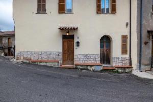Casa Romano في Polino: مبنى أبيض بأبواب خشبية على شارع