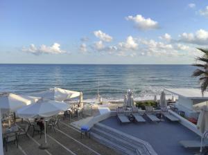 eine Terrasse mit Stühlen, Sonnenschirmen und dem Meer in der Unterkunft Filoxenia Beach Hotel in Rethymno