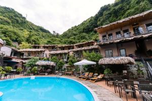 a hotel with a swimming pool and mountains in the background at Catba Oasis Bungalows in Cat Ba