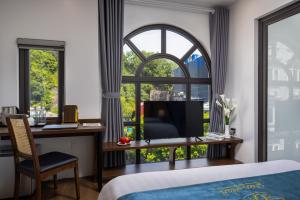 a bedroom with a desk and a large window at CatBa Green Pearl Hotel in Cat Ba