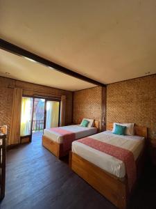 a hotel room with two beds and a window at Coral Voice 1 Homestay & Lumbung in Gili Trawangan