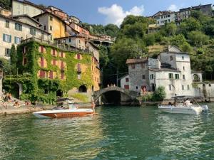 two boats in a river in front of buildings at Principessa Como close to the lake in Como