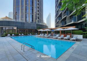 ein großer Pool mit Stühlen und Sonnenschirmen in der Unterkunft Address Opera - Lux 3 BR with Full Burj Khalifa View near Dubai Mall in Dubai