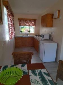 eine Küche mit einem weißen Kühlschrank und einem Tisch in der Unterkunft Dominic's Beach Bungalow in Muri