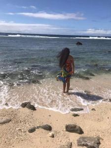 a young girl standing in the water at the beach at Dominic's Beach Bungalow in Muri