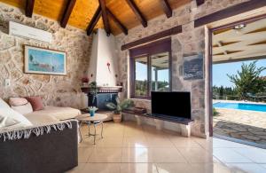 a living room with a couch and a tv at Key Villas in Tsoukalades