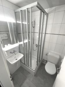 a bathroom with a shower and a toilet and a sink at Hotel Merkur - West Station in Interlaken